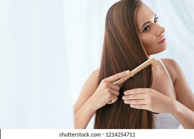 Hair Care. Woman Combing Beautiful Long Hair With Wooden Brush