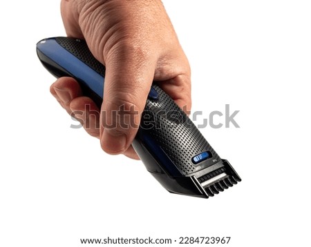 Hair clipper in hand isolated on white background. Modern hair clipper. Close-up.