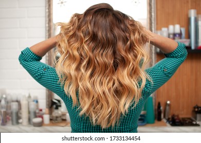 Hair coloring gradient from light golden to brown on a girl with long curly hair in the back
