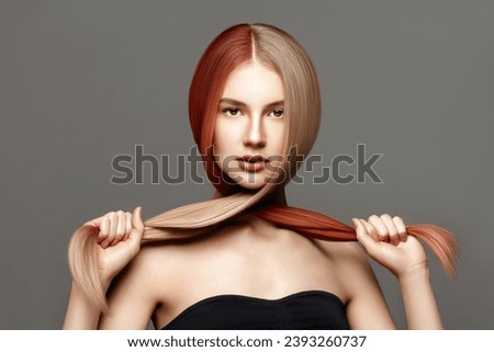 Hair coloring. Haircare. Beautiful young woman with long dyed toning healthy hair posing against grey background. Beauty salon concept 
