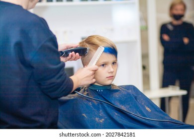 Hair Cutting For A Child In The Salon, A Hairdresser Cuts A Boy's Hair, A Beautiful Fashionable Haircut, Blue Bangs.
