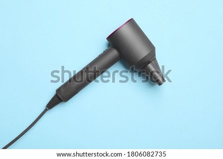 Hair dryer on light blue background, top view. Professional hairdresser tool
