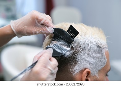 Hair dyeing for a young man in a hairdressing salon. the master bleaches the hair of the client - Powered by Shutterstock