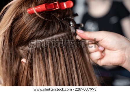 Hair extensions in a beauty salon, using capsules, girl at the hairdresser, hair clips, professional equipment, light blond hair, close-up, process, change of hairstyle on head Stock foto © 