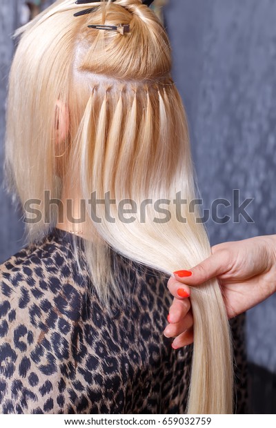 ヘアの拡張手順 美容師は 美容院で金髪の若い女の子に髪を伸ばす 限定フォーカス の写真素材 今すぐ編集
