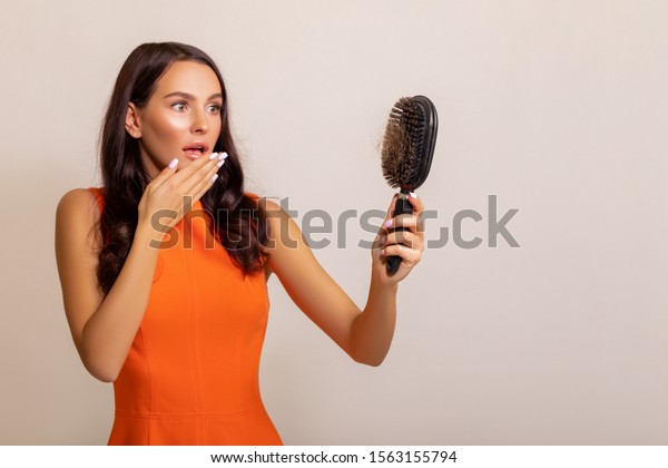 Hair fall
problem. Young caucasian woman with comb and problem hair on white
background.  loss. Beautiful girl looking hair loss from comb. Hair
care and beauty concepts. - Image 

