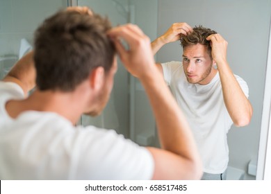 Hair Loss Man Looking In Bathroom Mirror Putting Wax Touching His Hair Styling Or Checking For Hair Loss Problem. Male Problem Of Losing Hairs.