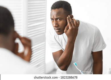 Hair Loss Problem. African American Man Looking In Mirror Touching Head Having Male-Pattern Baldness Issue Standing In Bathroom At Home. Men's Beauty And Haircare Treatment And Solutions Concept