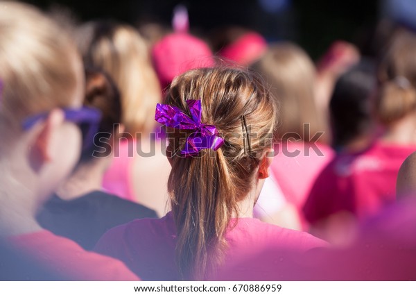 Hair pony tail with pink ribbon\
as a symbol for fighting cancer. Surrounded by ladies wearing pink\
all raising money to fight cancer. With a\
vignette.