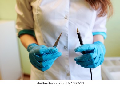 Hair Removal Equipment In The Doctor's Hands. Tweezers And Electrolysis Needle. Doctor's Hands In Blue Gloves. 