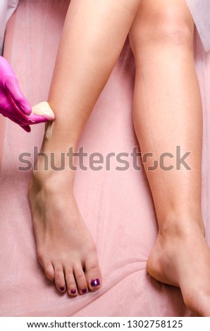Hair removal process on female leg with epilation. Hands of a beautician doctor doing a shugaring procedure close up on feet of a young woman.