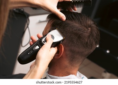 Hair salon master trimmed client hair with electric razor at barber shop. Male client getting haircut by hairdresser. Hair care, beauty industry, barber concept.