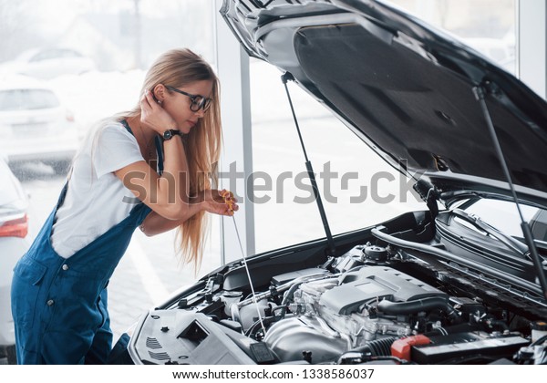 Hair starts to obstruct\
the look. On the lovely job. Car addicted woman repairs black\
automobile indoors.
