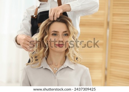 Hair styling. Professional hairdresser working with client indoors, closeup