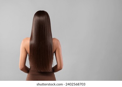 Hair styling. Woman with straight long hair on grey background, back view and space for text - Powered by Shutterstock