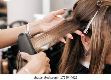 hair stylist creates volume and styling for brown hair on a woman's head in a beauty salon