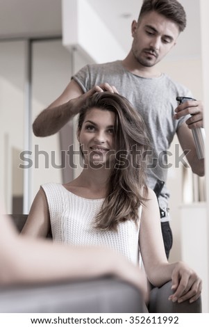 Hair stylist doing hairstyle for young woman