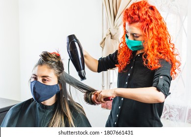 Hair Stylist Drying Female Client's Hair In Salon With A Face Mask