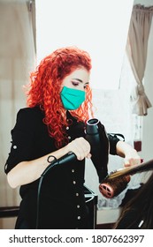 Hair Stylist Drying Female Client's Hair In Salon With A Face Mask