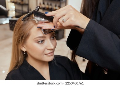 Hair stylist makes bouffant using comb on thin strands. Shatush technique for hair lightening - Shutterstock ID 2253480761