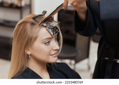 Hair stylist makes bouffant using comb on thin strands. Shatush technique for hair lightening - Shutterstock ID 2253480769