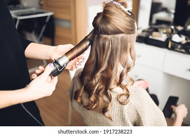 Hair Stylist Prepares Woman Makes Curls Hairstyle With Curling Iron. Long Light Brown Natural Hair