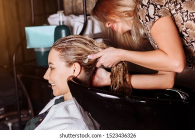 Hair stylist washing hair to the customer before doing hairstyle. Hairdresser applying nourishing mask. Hair wash shampoo, hair care products, spa. - Powered by Shutterstock