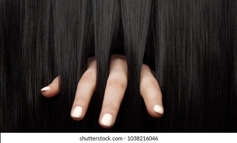 Hair texture background, no person. Black shiny hair Hands touching it fingers throught the hair