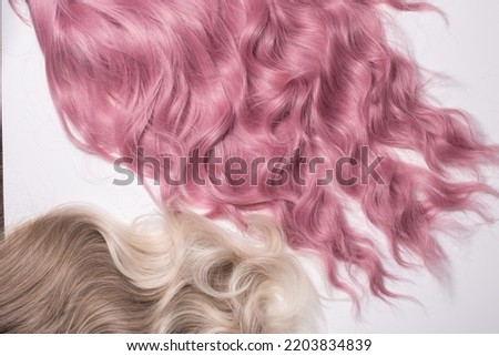 A hair texture of two hair colours: honey blond and rose pink closeups, a wavy shiny texture, isolated on white