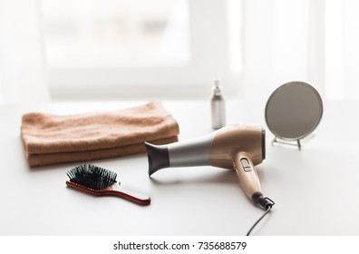 hair tools, beauty and hairdressing concept - hairdryer, brushes, mirror and towel on white background