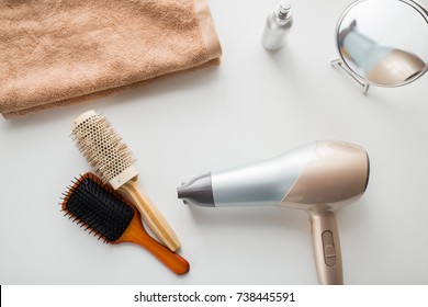 hair tools, beauty and hairdressing concept - hairdryer, brushes, mirror and towel on white background