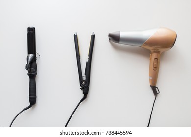hair tools, beauty and hairdressing concept - hairdryer, hot styler and curling iron or tongs on white background