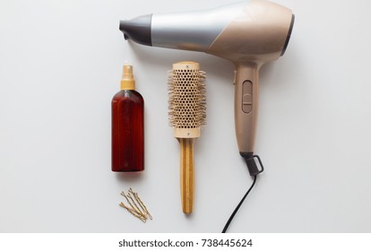 hair tools, beauty and hairdressing concept - hairdryer, brush, hot styling spray and pins on white background