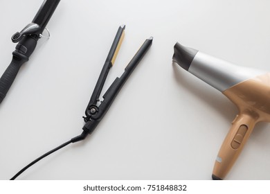 hair tools, beauty and hairdressing concept - hairdryer, hot styler and curling iron or tongs on white background