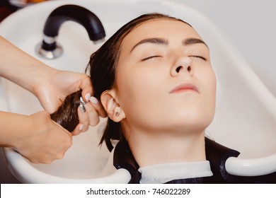 Hair washing. Master hairdresser washes client's head in sink