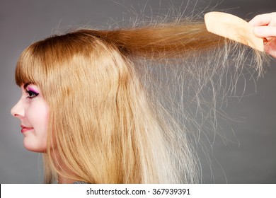 Haircare. Blonde woman with electrified long straight hair gray background