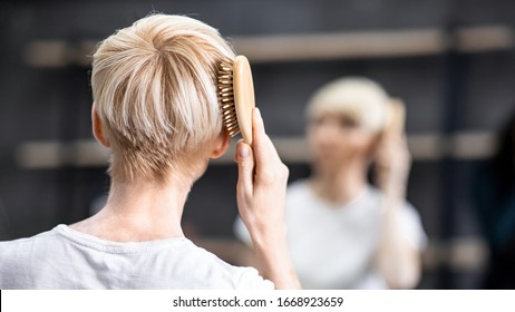 Haircare Concept. Unrecognizable Woman Brushing Hair Standing In Bathroom. Panorama, Selective Focus, Back View