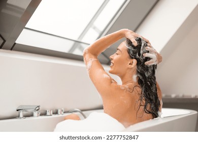 Haircare Cosmetics. Lady Applying Shampoo On Long Hair Washing Head Sitting In Bathtub Full Of Foam Indoors. Side View Shot Of Happy Woman Enjoying Hair Care Routine In Modern Bathroom - Shutterstock ID 2277752847