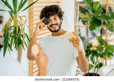 Haircare, Morning Routine, Eco Friendly, Sustainable Lifestyle Zero Waste Concept. Handsome Latin Curly Man Choosing Shampoo For Hair In Bathroom Interior At Home.