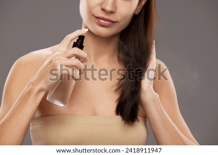 Haircare product advertisement showcasing a nourishing hair mist. Close-up of woman spraying product on her hair, focus on the spray mist. Concept of natural beauty, cosmetology, cosmetics, skin care