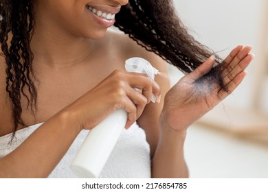 Haircare. Smiling Black Woman Applying Hair Spray To Split Ends, Young Happy African American Female Standing Wrapped In Towel After Shower Using New Hairstyle Product At Home, Closeup Shot