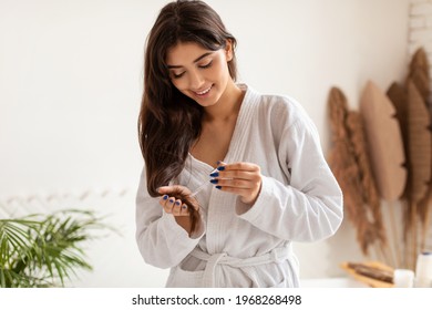 Haircare, Split Ends Treatment. Woman Applying Serum Or Essential Oil Caring For Damaged Dry Hair Posing Standing In Modern Bathroom At Home. Beauty Routine Concept