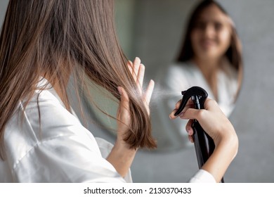 Haircare. Young Female Applying Hair Spray While Standing Near Mirror In Bathroom, Unrecognizable Millennial Woman Testing New Hairstyle Product At Home, Selective Focus On Her Reflection - Shutterstock ID 2130370433