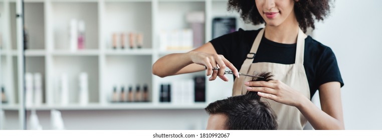 Haircut. Close up of hairdresser cutting hair of man in beauty salon interior, panorama, free space