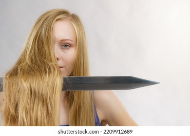 Haircut Coiffure Haircare Concept. Crazy Girl With Long Blonde Hair Holding Sword, Showing Tools For Haircutting