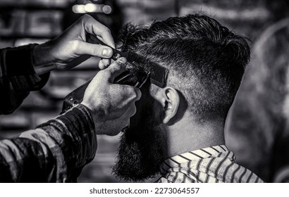 Haircut concept. Man visiting hairstylist in barbershop. Barber works with hair clipper. Hipster client getting haircut. Black and white - Powered by Shutterstock