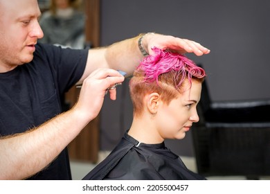 Haircut of dyed short pink wet hair of young caucasian woman by a male hairdresser in a barbershop - Shutterstock ID 2205500457