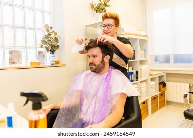 Hairdresser adjusting the capillary prosthesis to a man sitting in the salon - Powered by Shutterstock