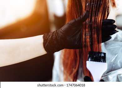 Hairdresser applies a redhead hair mask to the woman in the beauty salon. Botox and keratin hair straightening procedure