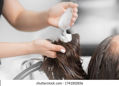 Hairdresser applies shampoo and hair conditioner client head. Concept spa beauty salon.